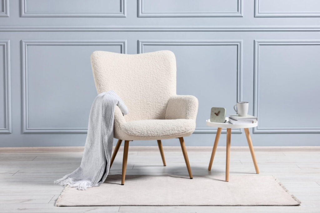 Chaise bouclette Meublissime associée à une ambiance cocooning avec une couverture, mettant en avant le confort et l’élégance dans un intérieur raffiné.
